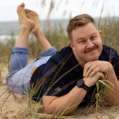 Matt Morgan relaxing on beach dunes, smiling at the camera